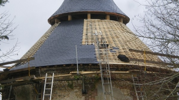 Pose d'ardoises sur une toiture conique en cours de rénovation